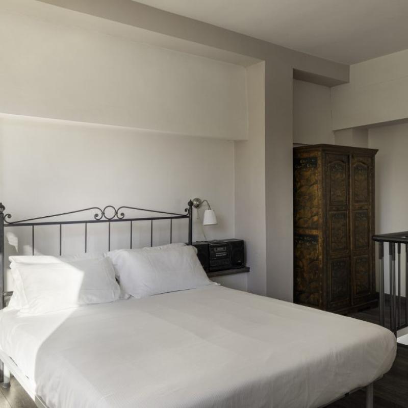 Camera da letto moderna con letto matrimoniale, armadio e pareti bianche.