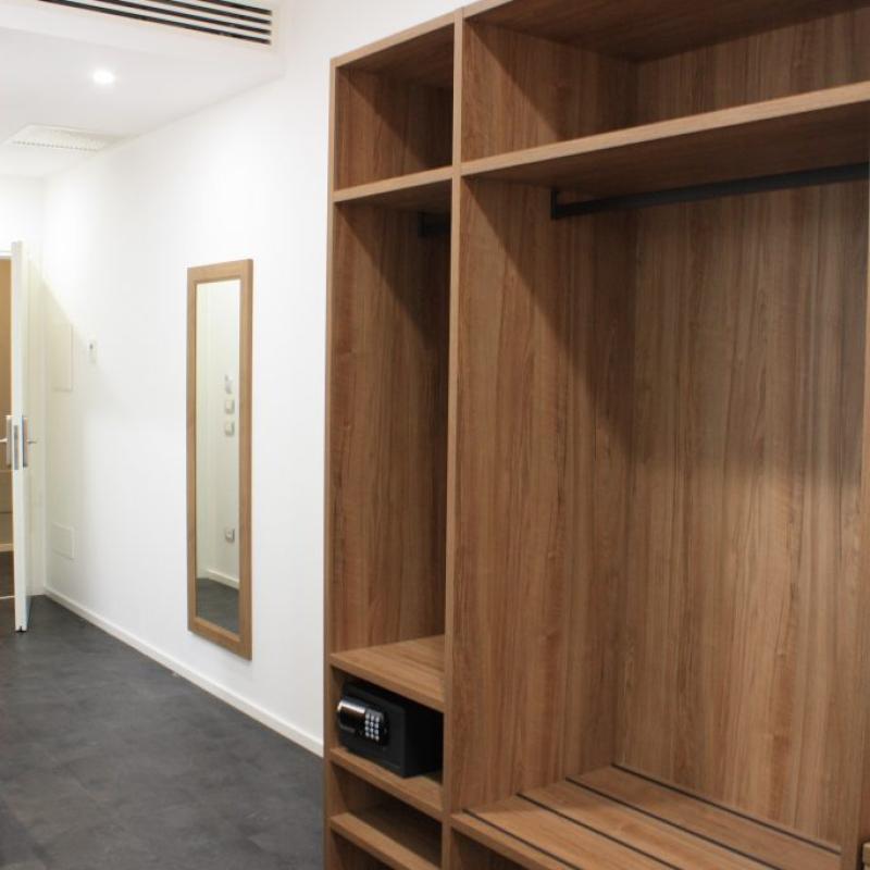 Spogliatoio moderno con armadietti in legno e cassaforte, specchio a parete.