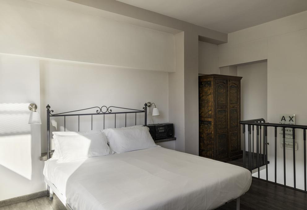 Camera da letto con letto matrimoniale, armadio antico e illuminazione moderna.
